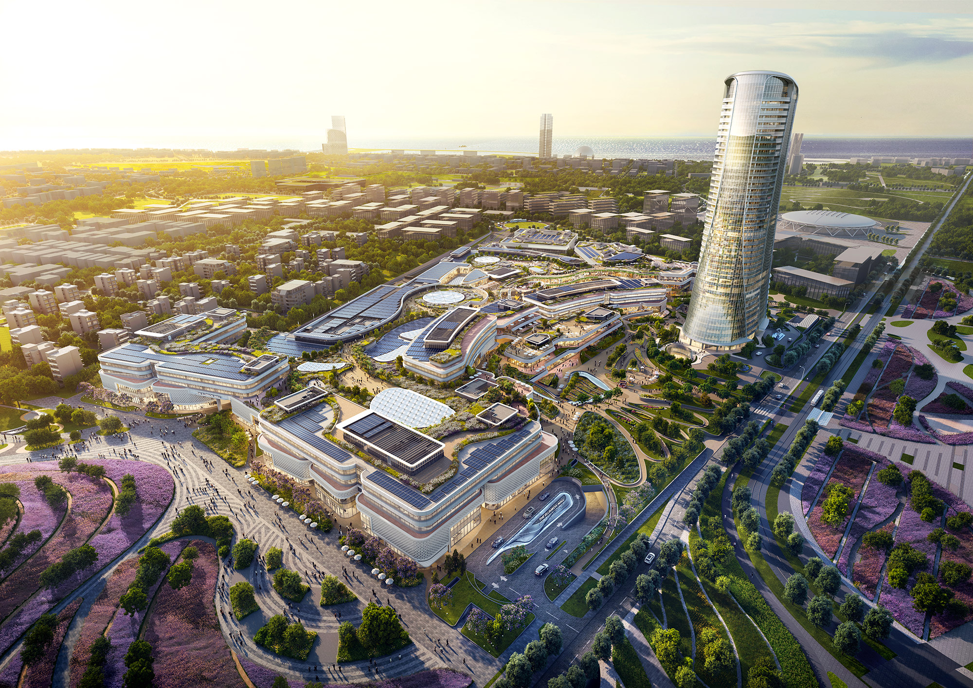 Aedas’ Ellinikon Commercial Hub in Athens with large-scale retail podiums, outdoor streetscapes and adjacent mixed-use tower. Aerial perspective of Aedas’ Ellinikon Commercial Hub showing expansive retail and leisure podiums with curvilinear roofs, outdoor pedestrian streets and landscaped terraces. A slender mixed-use tower rises alongside the mall complex. The development fronts Vouliagmenis Avenue and integrates shaded external circulation responding to the Mediterranean climate.
