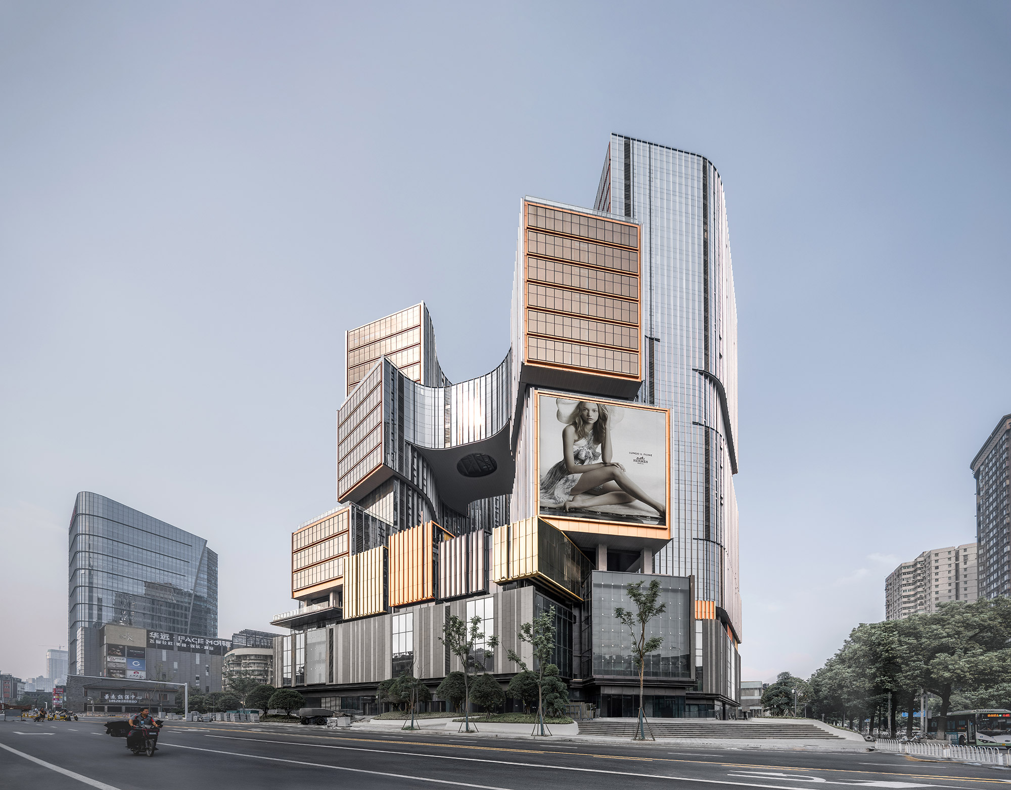 Aedas’ high-rise mixed-use tower with curved unitised glass façade, cantilevered volumes and integrated podium retail at urban crossroads. Street-level view of an Aedas mixed-use commercial tower featuring floor-to-ceiling curtain wall glazing, stacked and cantilevered office volumes, and a multi-storey podium. The podium integrates retail frontage, double-height glazing, and setback landscape zones along a wide arterial road within a dense urban environment.