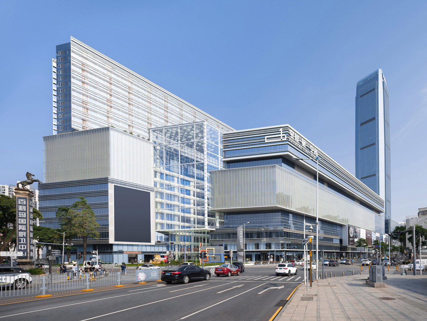 Aedas’ Baoneng Centre in Shenzhen with layered glass façades, multi‑storey podium and high‑rise towers in Sungang. Street‑level view of Aedas‑designed Baoneng Centre in Shenzhen, showing an expansive mixed‑use complex with a multi‑storey podium articulated by layered glass curtain walls and horizontal bands. Above, a tall Grade‑A office tower and ancillary towers rise from the podium, while glazed atrium volumes and urban streetscape interfaces define the development’s public edge.