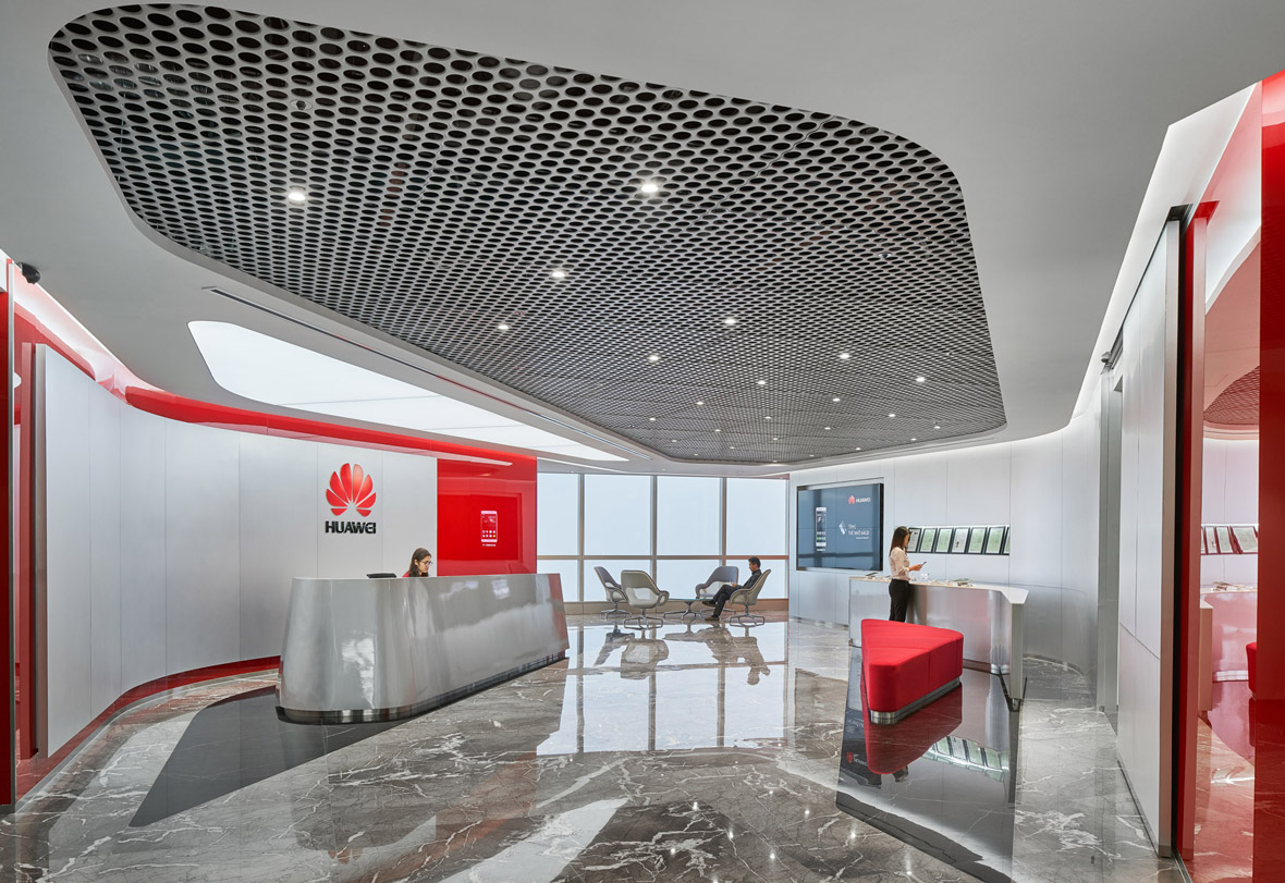 Aedas Interiors’ Huawei Hanoi office is shown with a refined reception environment featuring sculpted metallic counters, a perforated geometric ceiling panel, polished stone flooring, and integrated brand graphics. The image highlights a cohesive corporate interior language enriched with local material accents, varied spatial identities, and colour infusions that create a welcoming, contemporary workplace aligned with Huawei’s global design ethos.