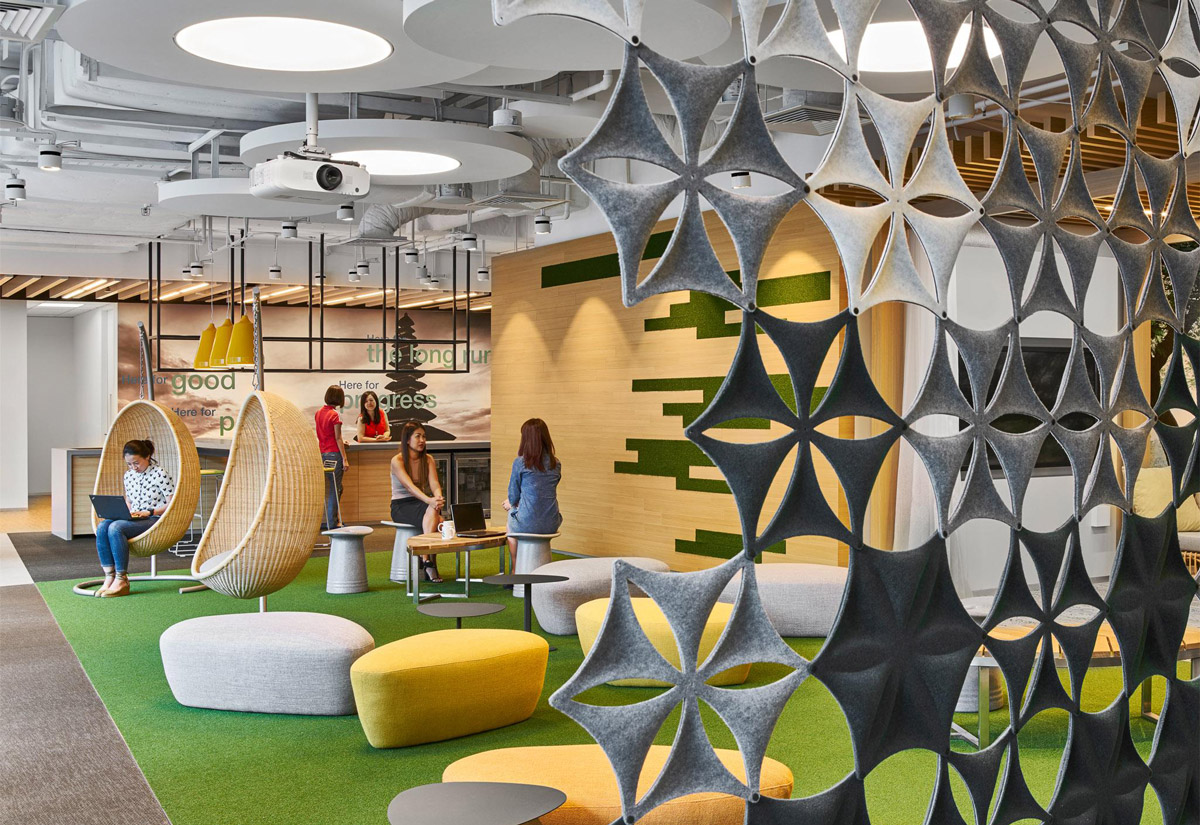 Aedas Interiors’ Changi Business Park 2 is shown with a vibrant agile workplace featuring modular breakout seating, sculptural felt partition screens, suspended acoustic elements, and integrated meeting hubs. The image highlights a flexible, activity‑based interior environment with clear departmental zoning, informal collaboration areas, and thoughtful wayfinding integrated into a contemporary financial workplace.