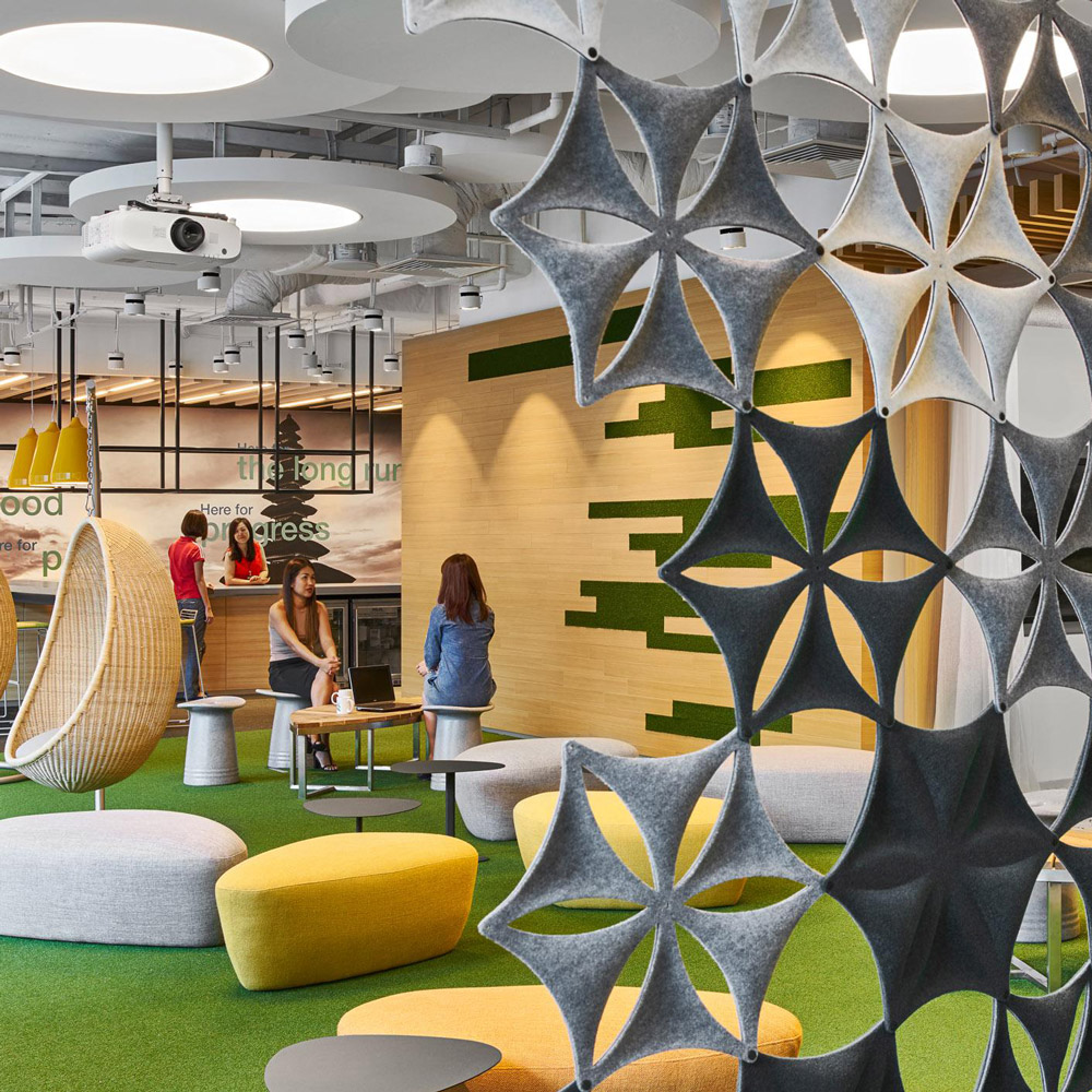 Aedas Interiors’ Changi Business Park 2 is shown with a vibrant agile workplace featuring modular breakout seating, sculptural felt partition screens, suspended acoustic elements, and integrated meeting hubs. The image highlights a flexible, activity‑based interior environment with clear departmental zoning, informal collaboration areas, and thoughtful wayfinding integrated into a contemporary financial workplace.