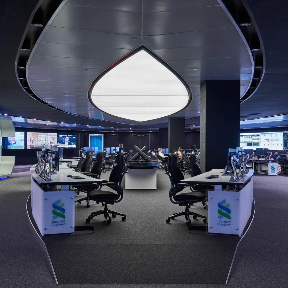 Aedas Interiors’ Standard Chartered Bank Global Command Centre in Kuala Lumpur is shown as a highly secure, fully digitised operations space with radial workstation clusters, immersive multi‑screen monitoring walls, and a sculptural fingerprint‑inspired ceiling form. The image highlights futuristic interior architecture designed for global network control, real‑time data visualisation, and visitor engagement within a mission‑critical banking environment.