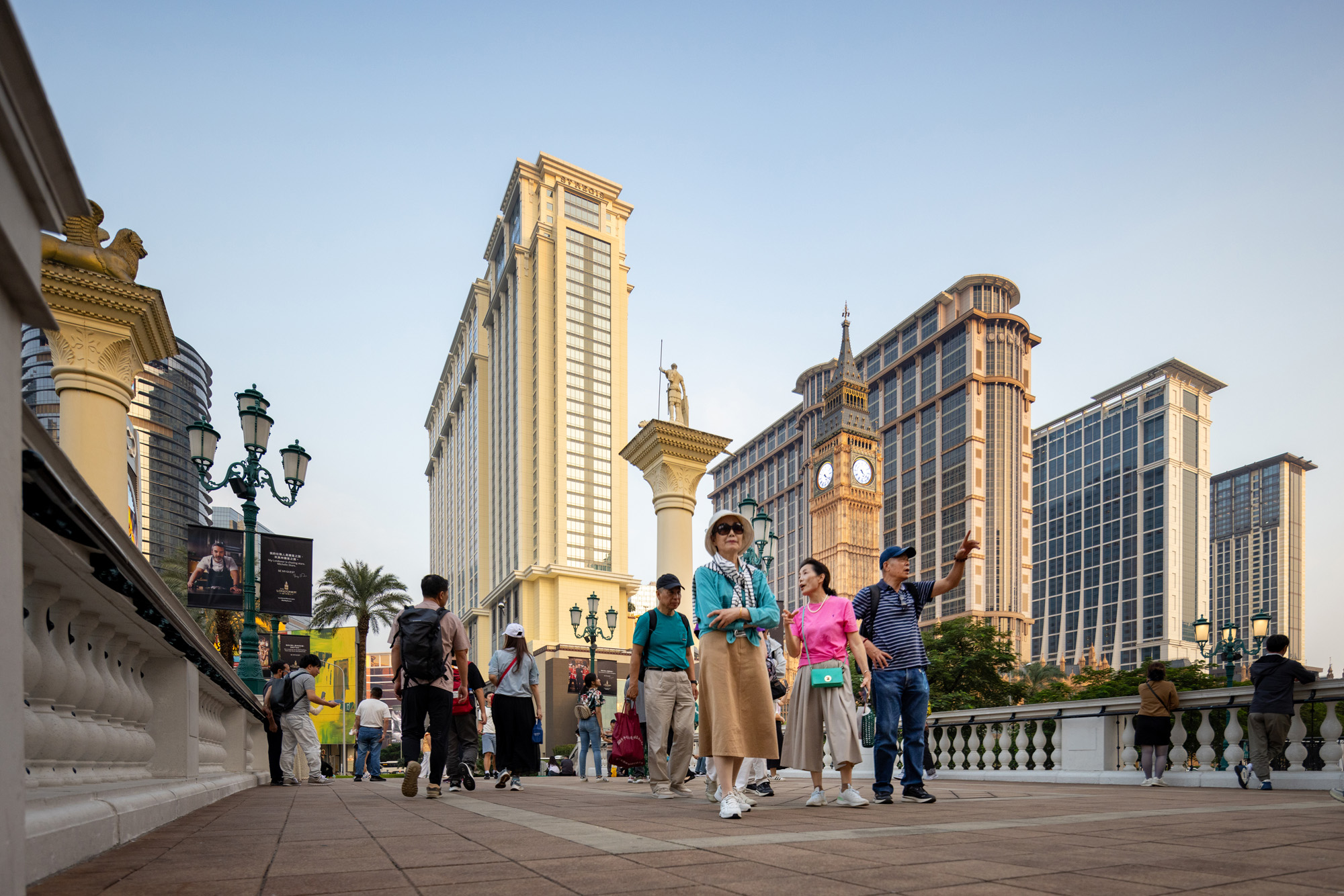 Aedas’ Londoner Macao integrated resort promenade with hotel towers, classical façades and public realm at Cotai. Street‑level view of Aedas‑designed The Londoner Macao, showing a pedestrian promenade framed by multi‑storey hotel towers with classical detailing, glazed façades and articulated cornices. Replica landmark elements and lantern‑style street lighting define the public realm, with podium levels accommodating retail entrances and covered walkways within the Cotai integrated‑resort district.