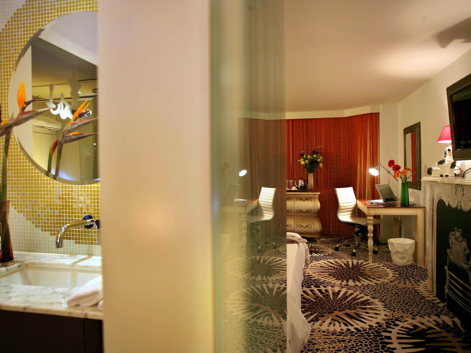 Aedas Interiors’ The Luxe Manor guest room in Hong Kong is shown as an eclectic boutique hotel interior combining vintage‑inspired furnishings, patterned carpeting, and layered lighting with contemporary detailing. The image highlights a playful yet refined accommodation space where traditional motifs, curated decorative elements, and bespoke furniture create a homely, theatrical atmosphere that reinterprets classic bedroom grandeur with a modern twist.