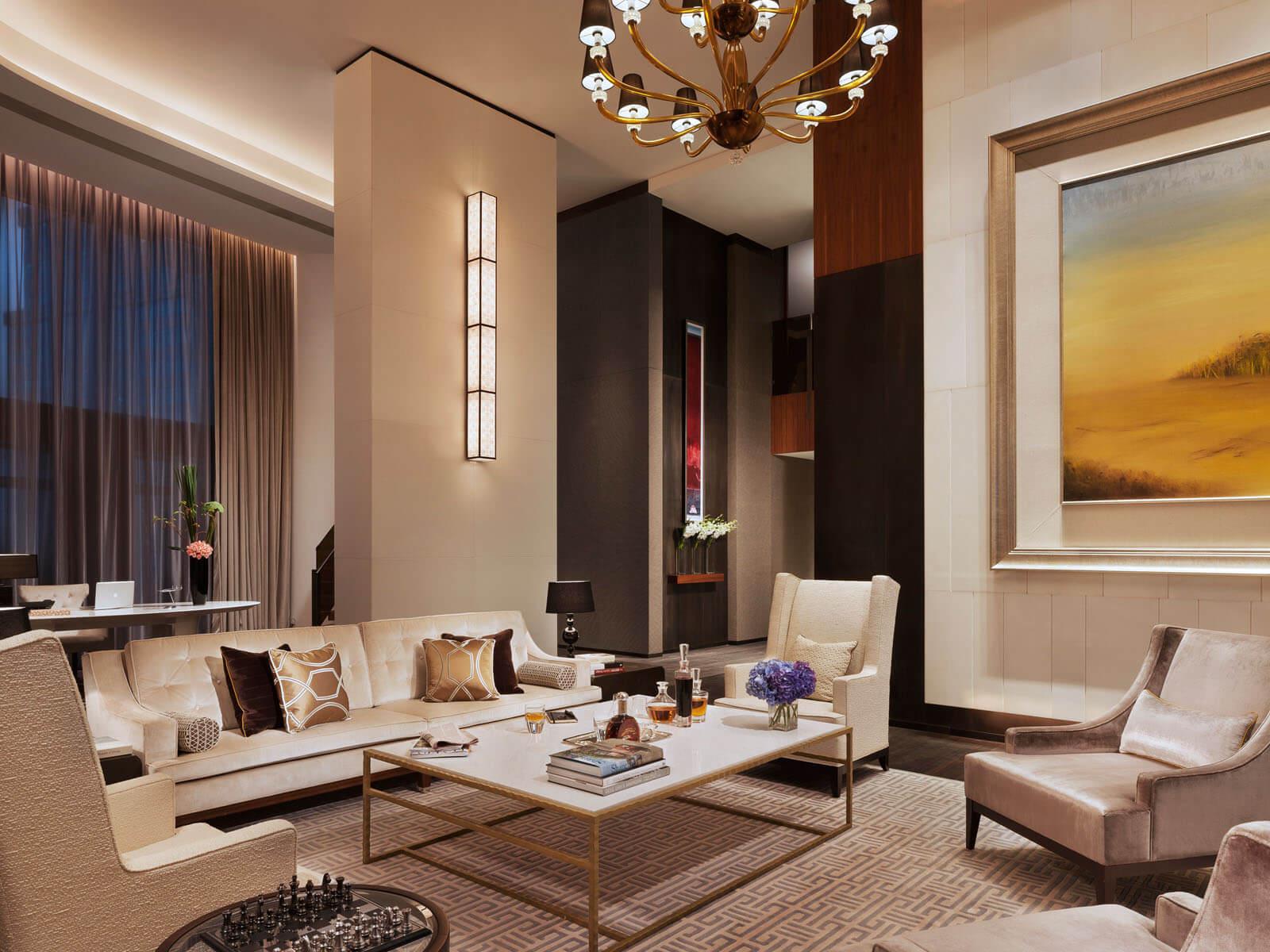 Aedas Interiors’ The Langham Xintiandi in Shanghai is shown as an elegant executive lounge featuring plush upholstered seating, dark timber wall panels, soft neutral finishes, and classic chandelier lighting. The image highlights a refined rebranding interior that introduces European traditional elegance through updated FF&E, curated artwork, and layered lighting while seamlessly enhancing existing spaces to align with The Langham’s luxury identity.