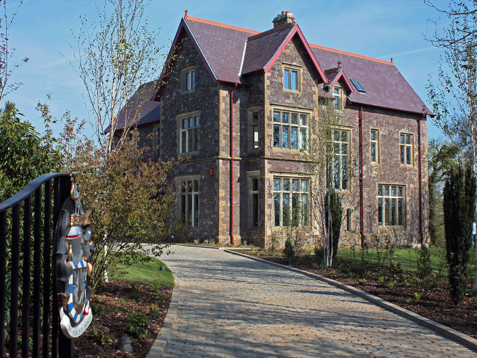 Aedas Interiors’ restored Penrhiw Hotel in St Davids, UK is shown as a historic stone manor with pitched slate roofs, mullioned windows, and mature landscaped grounds. The image highlights heritage architecture constructed of local Caerbwdi stone and Bathstone, carefully refurbished to form an intimate luxury hotel that preserves original craftsmanship while establishing a refined, secluded hospitality setting.