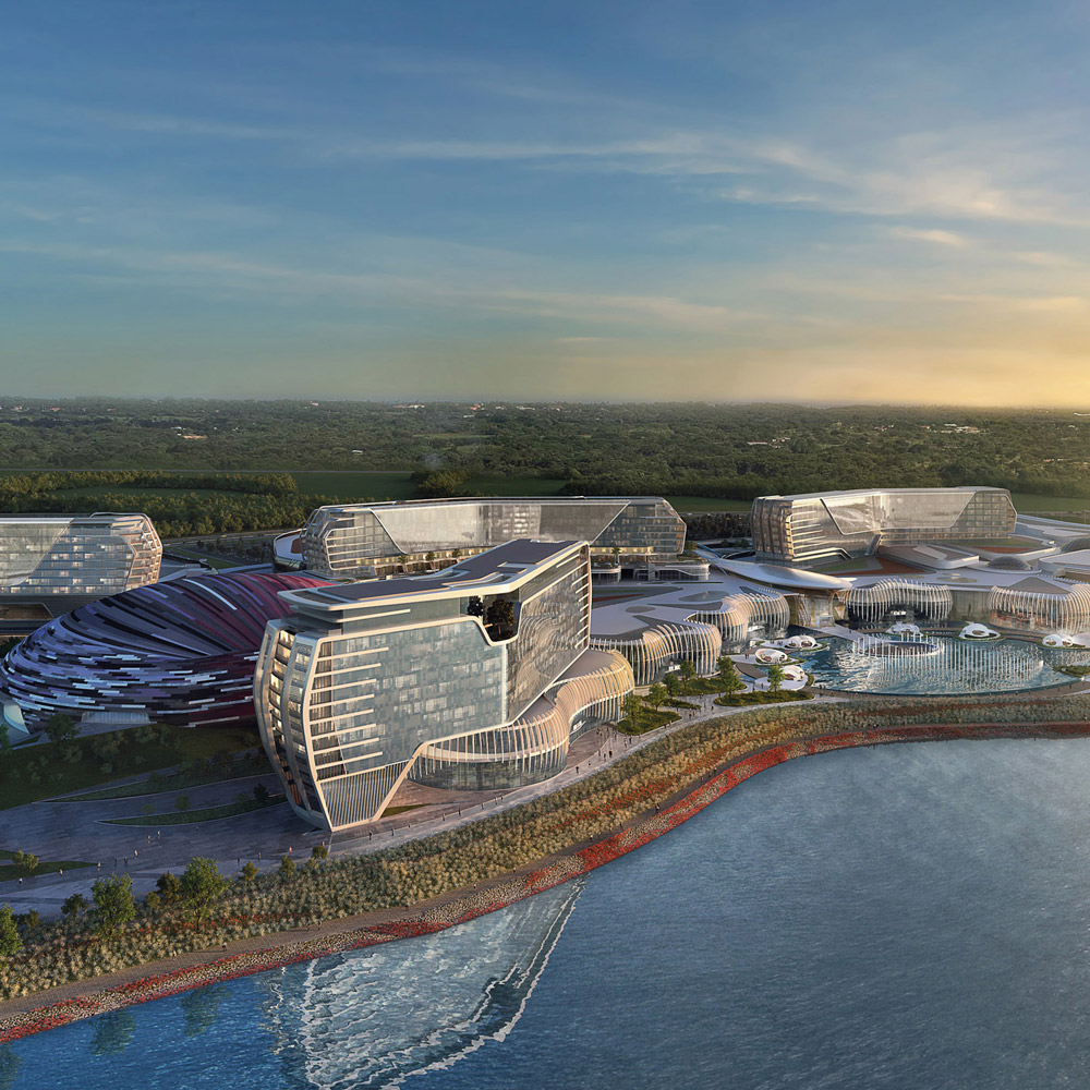 Aedas’s Inspire Integrated Resort in Incheon is shown as a large-scale waterfront development composed of multiple sculpted hotel volumes, curved podium structures, and extensive landscaped terraces. The aerial view highlights horizontal resort massing, glazed façades, and integration of water features and public circulation within a coastal setting.
