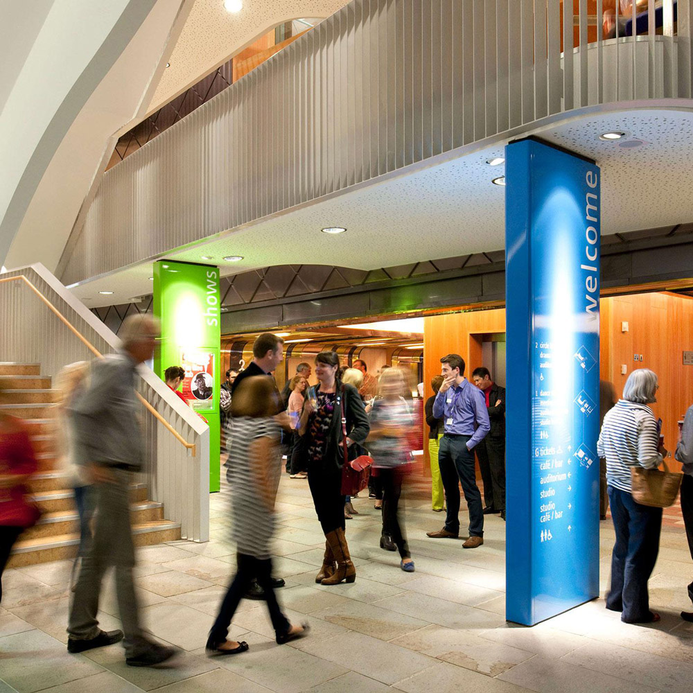 Aedas’s Cast theatre in Doncaster is shown with a multi‑level foyer architecture featuring exposed structural columns, sculpted stair elements, mezzanine galleries, and glazed internal frontages. The image highlights civic cultural architecture, adaptable public circulation space, and robust building systems supporting contemporary performance venues in the UK.