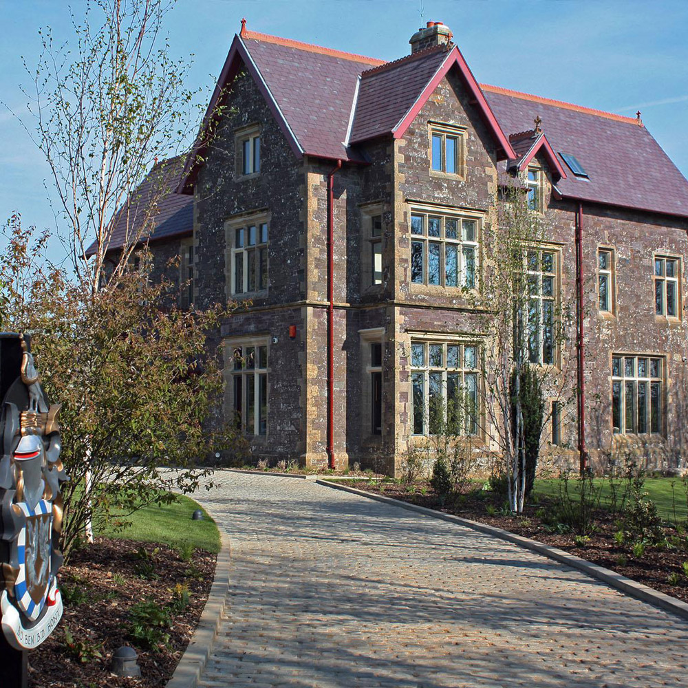 Aedas Interiors’ restored Penrhiw Hotel in St Davids, UK is shown as a historic stone manor with pitched slate roofs, mullioned windows, and mature landscaped grounds. The image highlights heritage architecture constructed of local Caerbwdi stone and Bathstone, carefully refurbished to form an intimate luxury hotel that preserves original craftsmanship while establishing a refined, secluded hospitality setting.