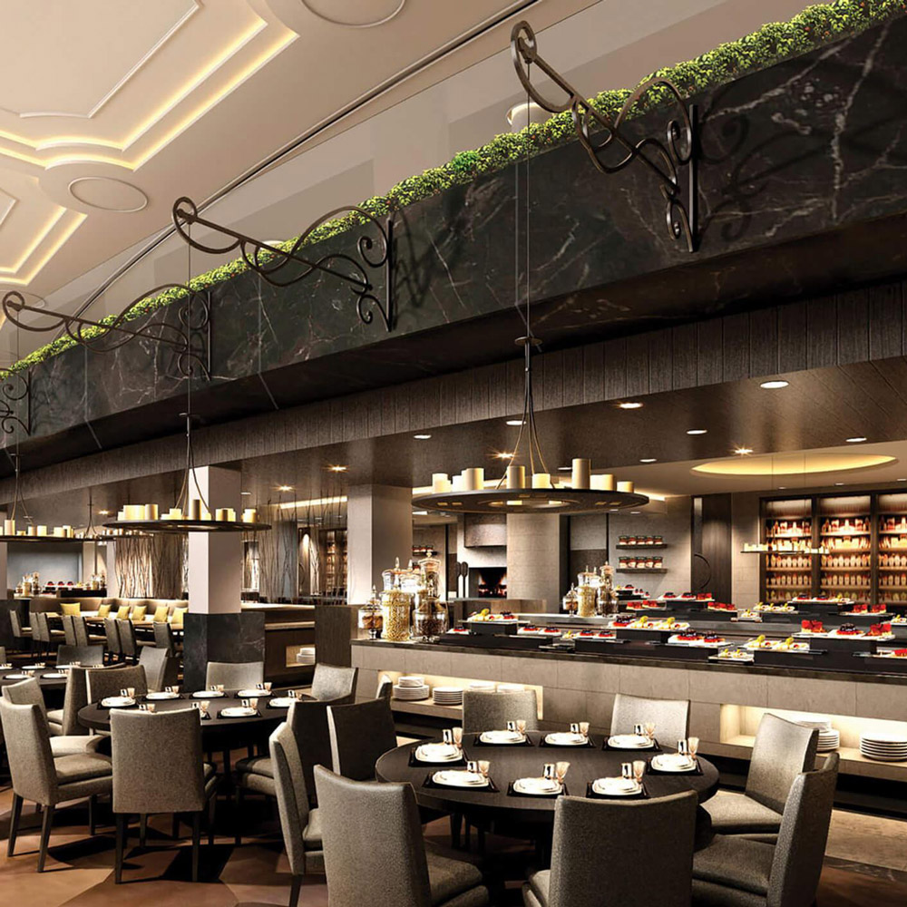 Aedas Interiors’ All-day Dining Restaurant in Wuhan is shown as an elegant, open dining space with a long buffet counter, marble finishes, and layered seating arrangements beneath delicate chandelier lighting. The image highlights a contemporary hospitality interior where soft illumination, refined materials, and balanced proportions create a warm, graceful atmosphere suitable for continuous daytime dining.