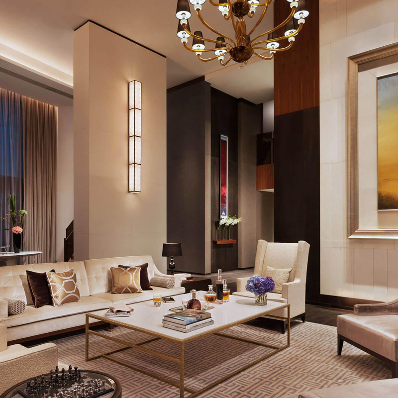 Aedas Interiors’ The Langham Xintiandi in Shanghai is shown as an elegant executive lounge featuring plush upholstered seating, dark timber wall panels, soft neutral finishes, and classic chandelier lighting. The image highlights a refined rebranding interior that introduces European traditional elegance through updated FF&E, curated artwork, and layered lighting while seamlessly enhancing existing spaces to align with The Langham’s luxury identity.