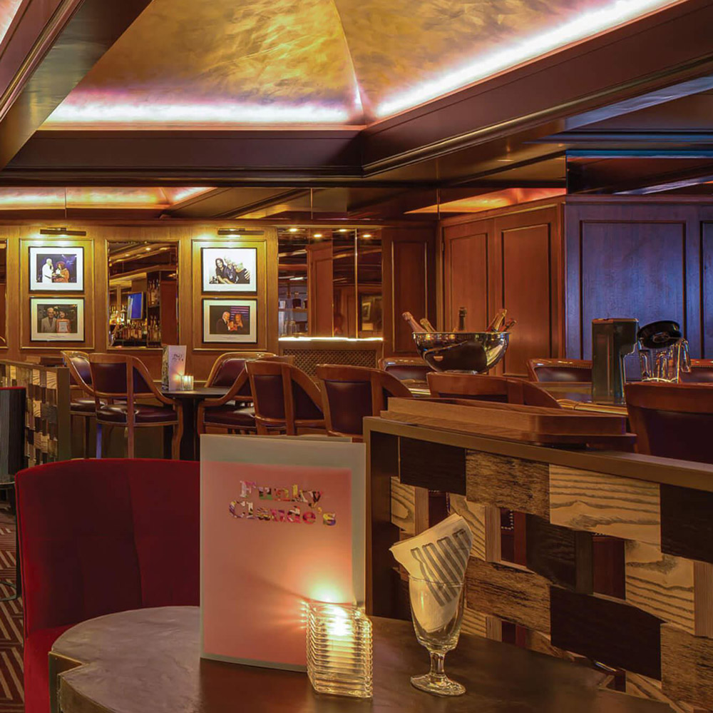 Aedas Interiors’ Montreux Jazz Café at Fairmont Le Montreux Palace is shown as a richly layered hospitality interior with warm timber walls, mirrored surfaces, curated music memorabilia, and intimate lounge seating. The image highlights a narrative‑driven dining environment inspired by jazz culture, using refined lighting, eclectic furnishings, and artisanal detailing to evoke the legacy and atmosphere of the Montreux Jazz Festival.