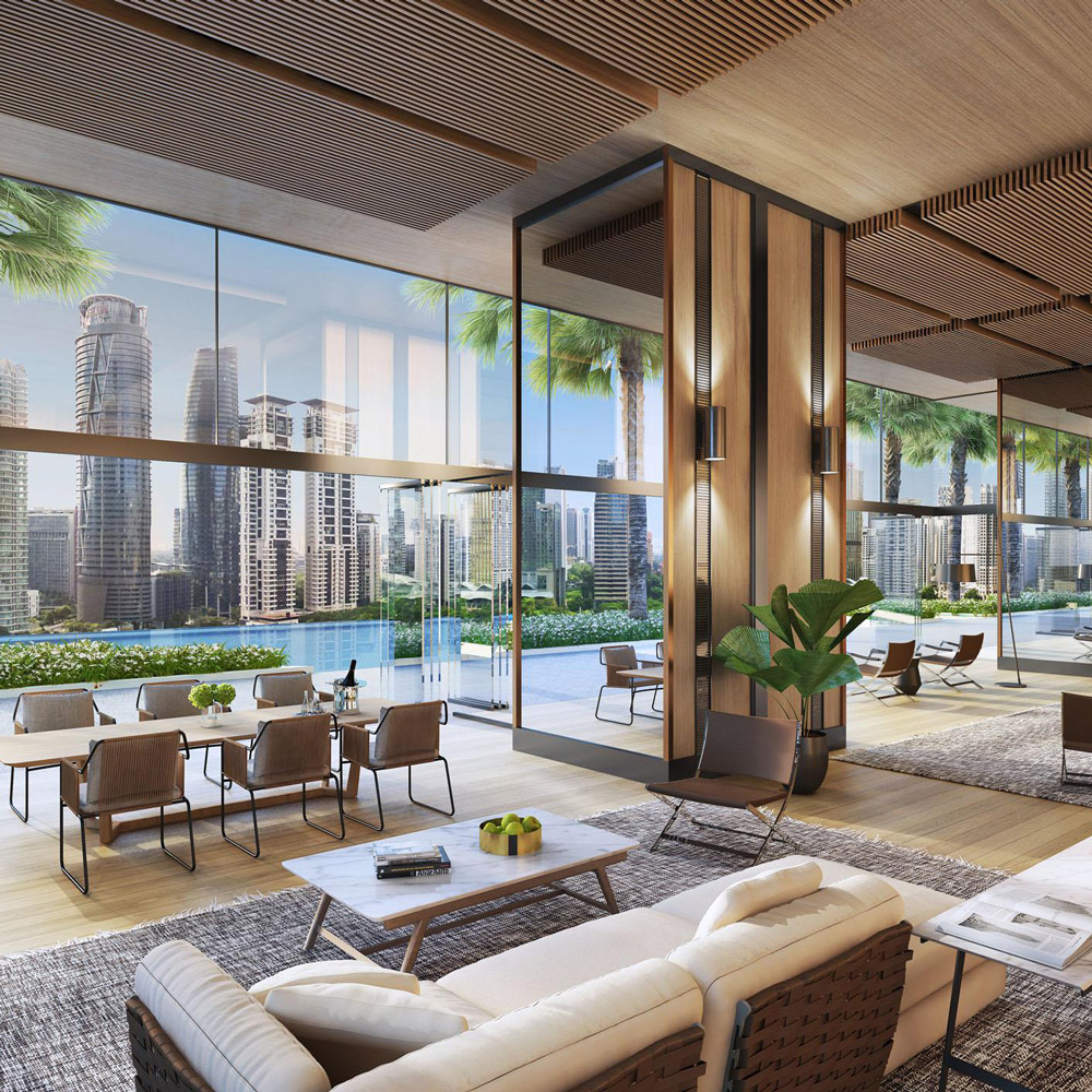 Aedas Interiors’ Jumeirah Residences Kuala Lumpur is shown as an open residential lounge with full‑height glazing overlooking a landscaped terrace and city skyline. The interior features timber slatted ceilings, warm neutral furnishings, integrated greenery, and flexible seating areas, highlighting a refined, resort‑style living environment that blends indoor–outdoor continuity with contemporary residential luxury.