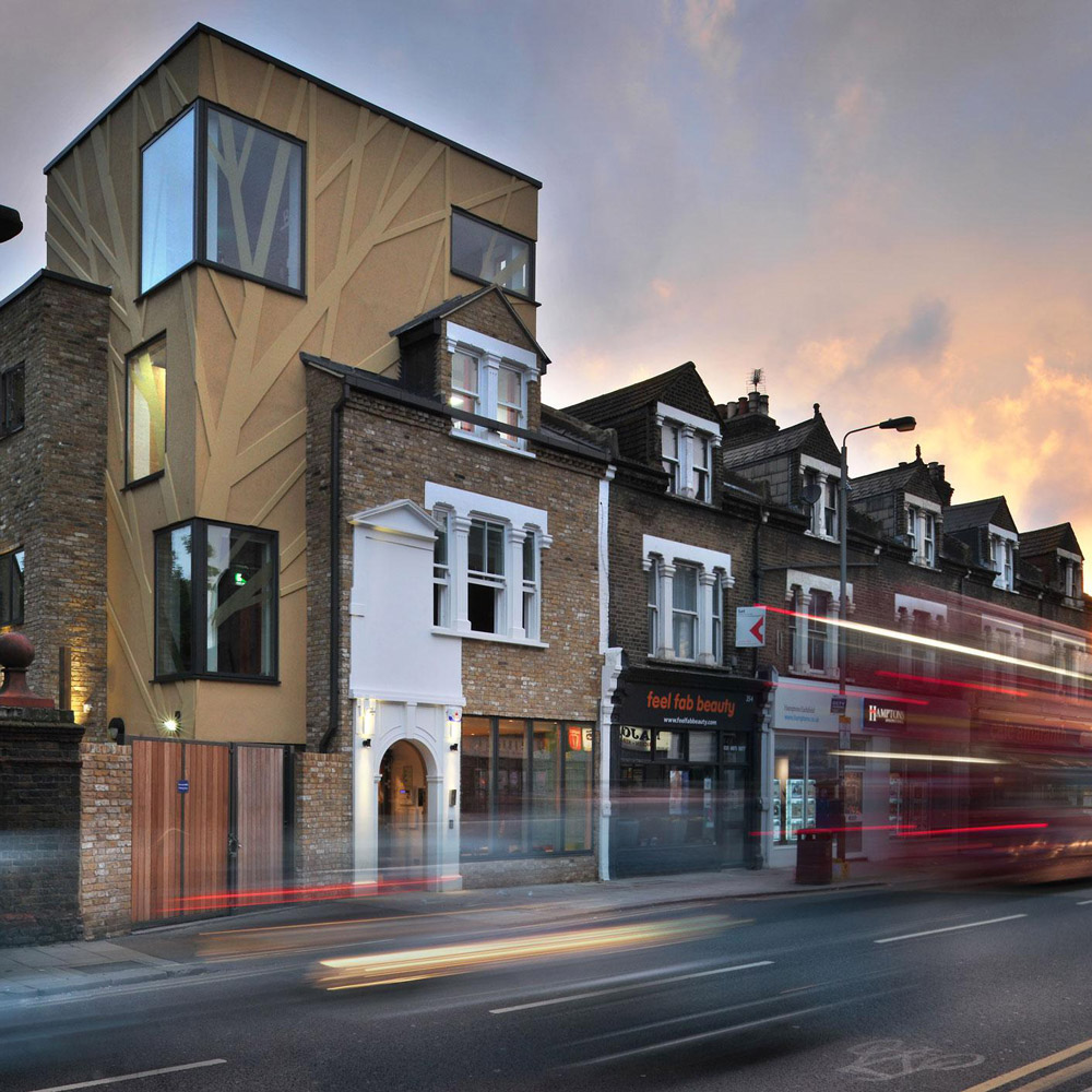 Aedas’s Tara Theatre in London is shown as a contemporary infill cultural building with angular massing, prefabricated façade panels, irregular window apertures, and a compact vertical form. The street‑level view highlights adaptive reuse, tight urban integration, and performance‑led architecture within a dense UK high‑street context.