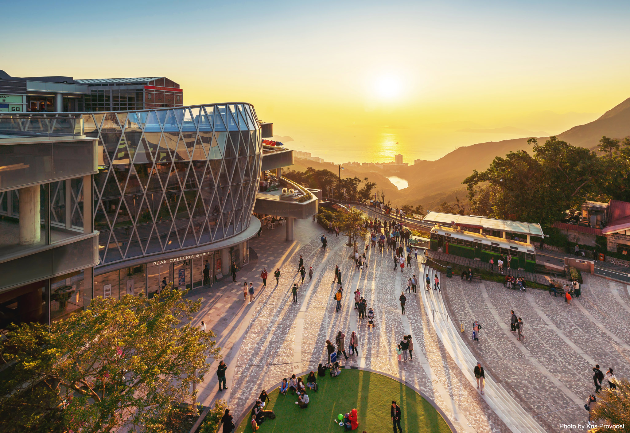 Aedas’s Peak Galleria in Hong Kong is shown as a hilltop retail destination with a faceted glazed façade, elevated pedestrian plaza, and stepped circulation. The image highlights transparent enclosure systems, public‑realm integration, and landscape‑responsive architecture positioned along Victoria Peak’s transport and viewing corridor.