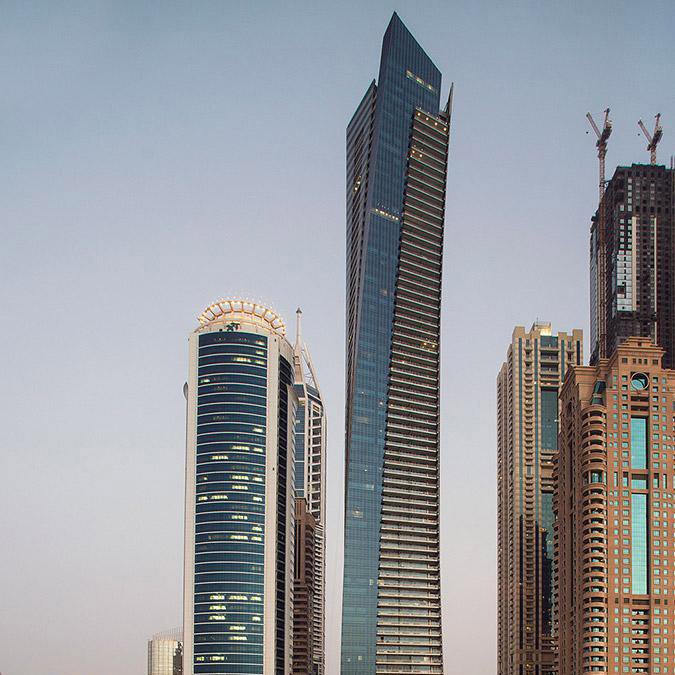 Aedas’s Ocean Heights in Dubai is shown as a tall residential tower with a sculpted twisting profile, continuous vertical glazing, and tapered floor plates that articulate a dynamic skyline presence. The exterior highlights high‑rise residential architecture, aerodynamic massing, and integration within Dubai’s dense coastal development corridor.