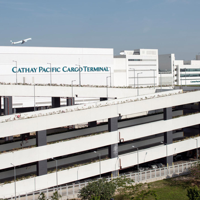Aedas’ Cathay Pacific Cargo Terminal at Hong Kong International Airport is shown as a large‑scale logistics complex with linear white‑clad façades, horizontal louvers, and integrated service decks. The image highlights a highly efficient aviation infrastructure designed for high‑volume cargo handling, featuring clear functional articulation, expansive floor plates, and a streamlined architectural expression that reinforces Hong Kong’s role as a global air‑freight hub.