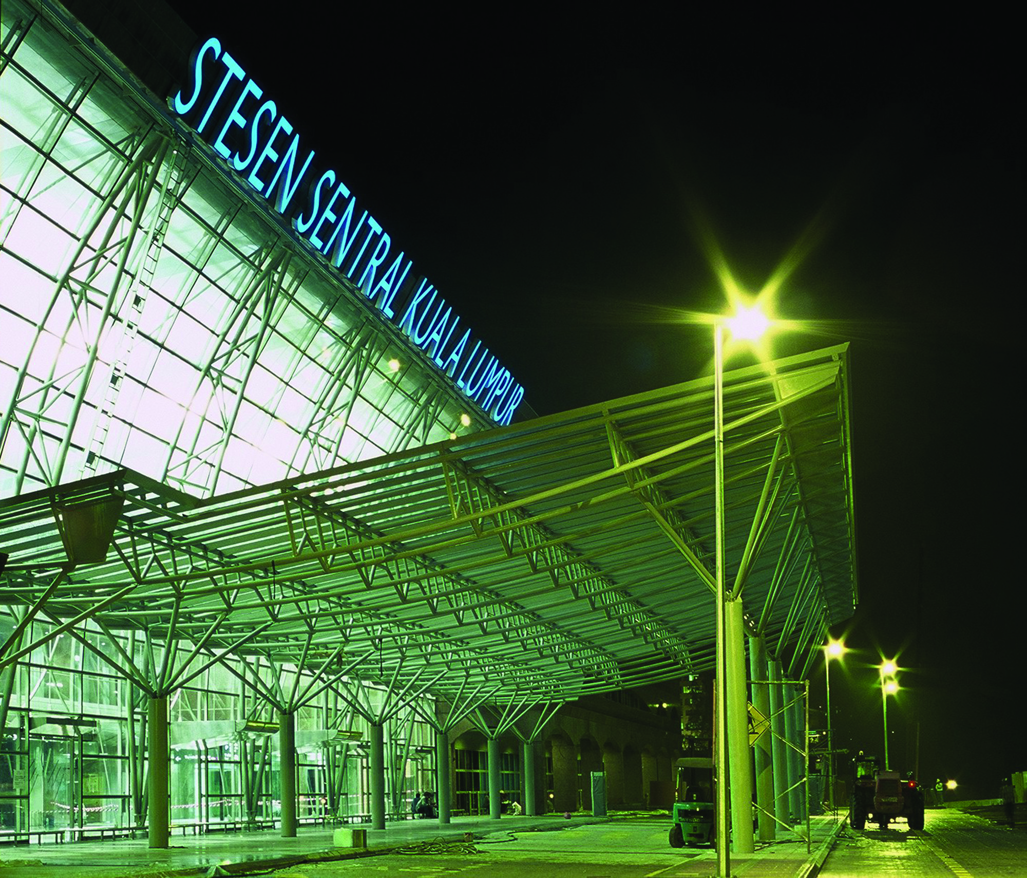 Aedas’ Kuala Lumpur Sentral is shown at night as a major transit concourse defined by expansive steel canopies and glass façades illuminated from within. The image highlights the hyperbolic paraboloid roof structure constructed in exposed steel and stainless steel cladding, framing the station entrance and conveying a sense of openness, movement, and civic scale befitting Malaysia’s primary integrated transport hub.