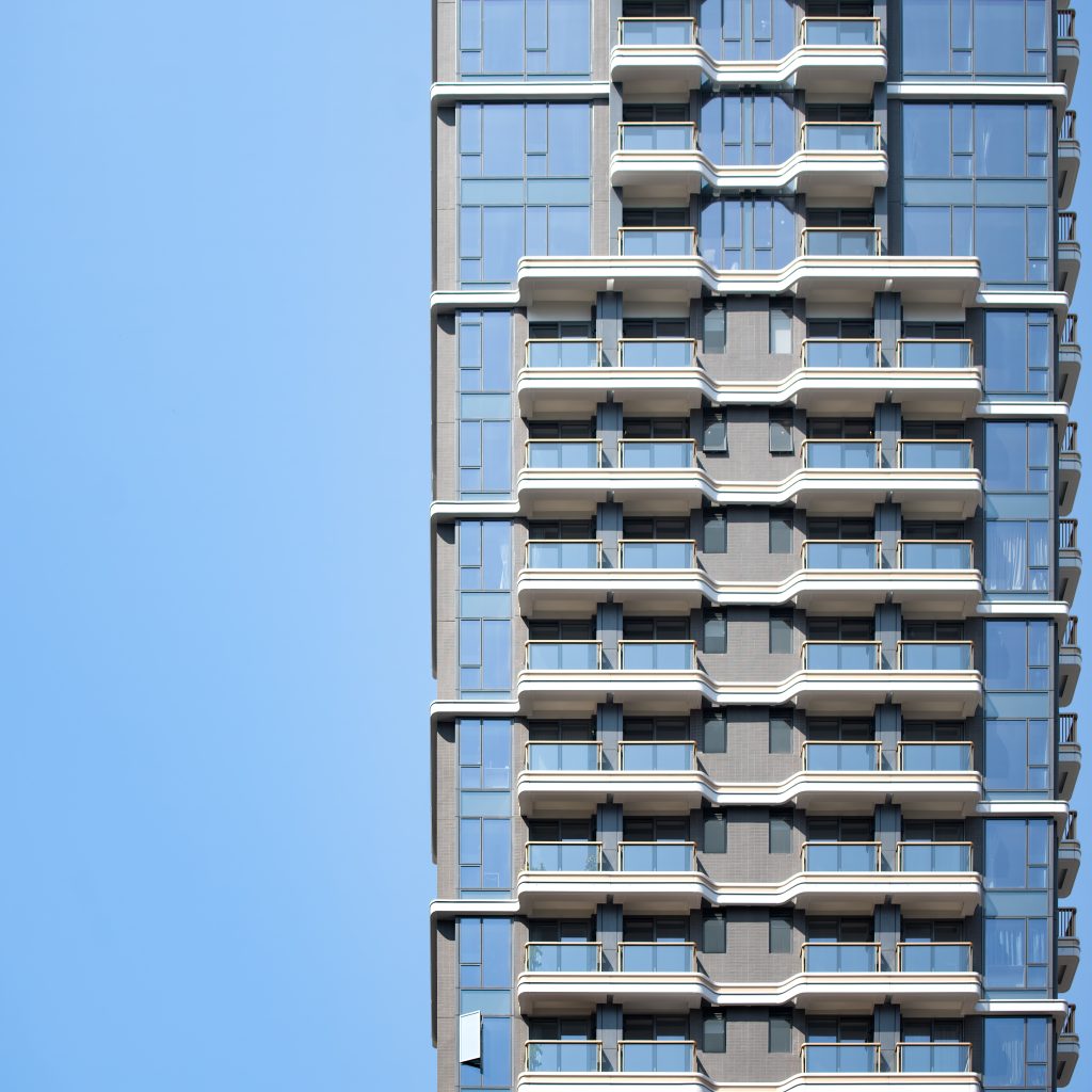 Aedas’ The Nova Residential Development in Hong Kong is shown as a slender residential tower with a rhythmic façade of projecting balconies framed by light‑coloured horizontal bands and glazed balustrades. The image highlights a clean, contemporary elevation where stacked geometries, high‑performance curtain wall glazing, and articulated balcony forms create depth, maximise natural light, and establish a refined modern residential identity within the dense Sai Ying Pun skyline.