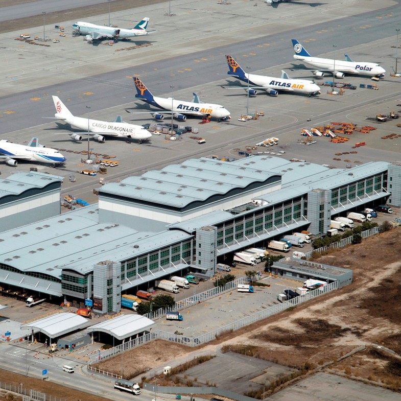 Aedas’s Asia Airfreight Terminal 1 at Hong Kong International Airport is shown as a large‑scale logistics facility with long‑span metal roof structures, repetitive industrial bays, and integrated service façades. The aerial view highlights airport‑adjacent infrastructure architecture designed for high‑volume cargo handling within a dense aviation environment.