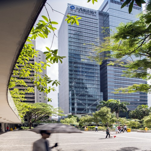 Aedas’ China Construction Bank Tower in Hong Kong is shown as a sleek Grade‑A office tower along the Central waterfront, characterised by a disciplined vertical glass façade with strong linear articulation and stepped massing. The image highlights a refined corporate landmark framed by Victoria Harbour and mountain backdrops, conveying institutional authority, elegance, and clarity within Hong Kong’s dense financial skyline.