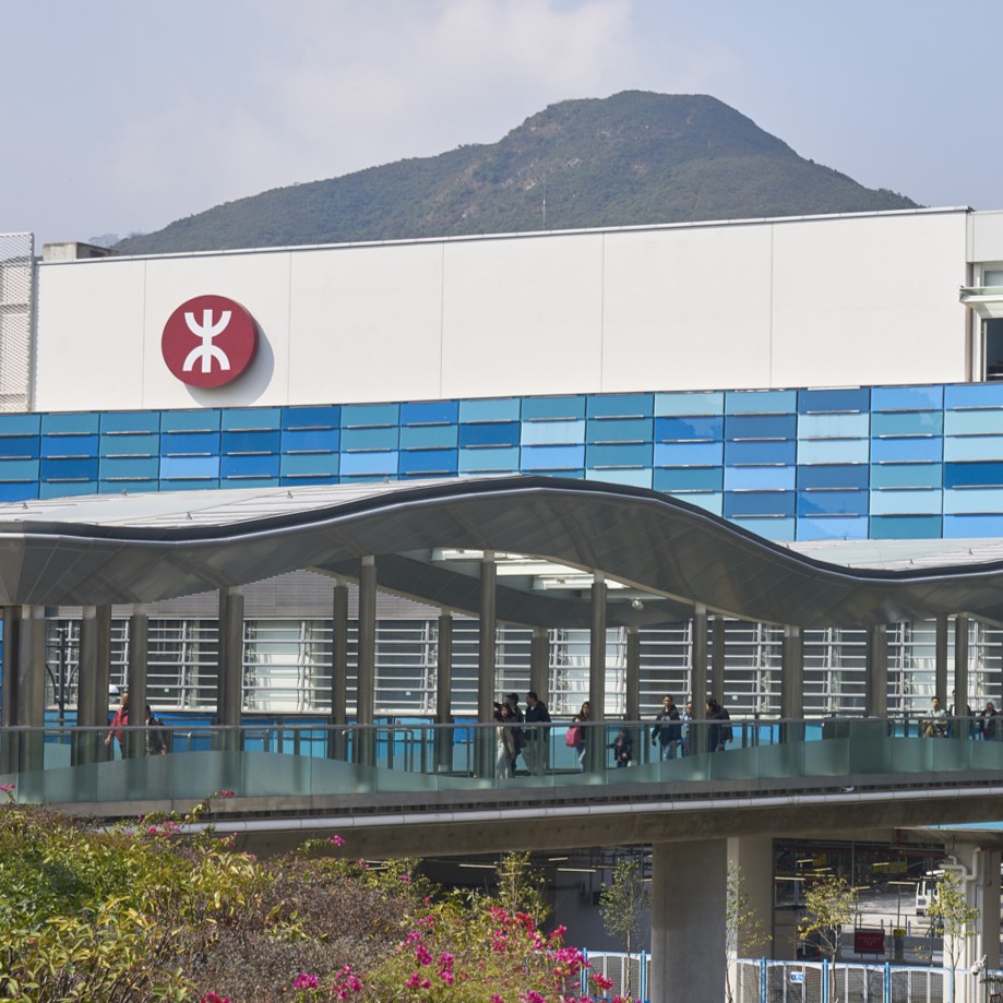 Aedas’s Ocean Park Station on the MTR South Island Line is shown with an elevated pedestrian approach, steel column supports, long-span canopy roof, glazed balustrades, and integrated station signage. The image highlights transport architecture focused on weather protection, passenger flow, and seamless connection between station and surrounding urban landscape in Hong Kong.