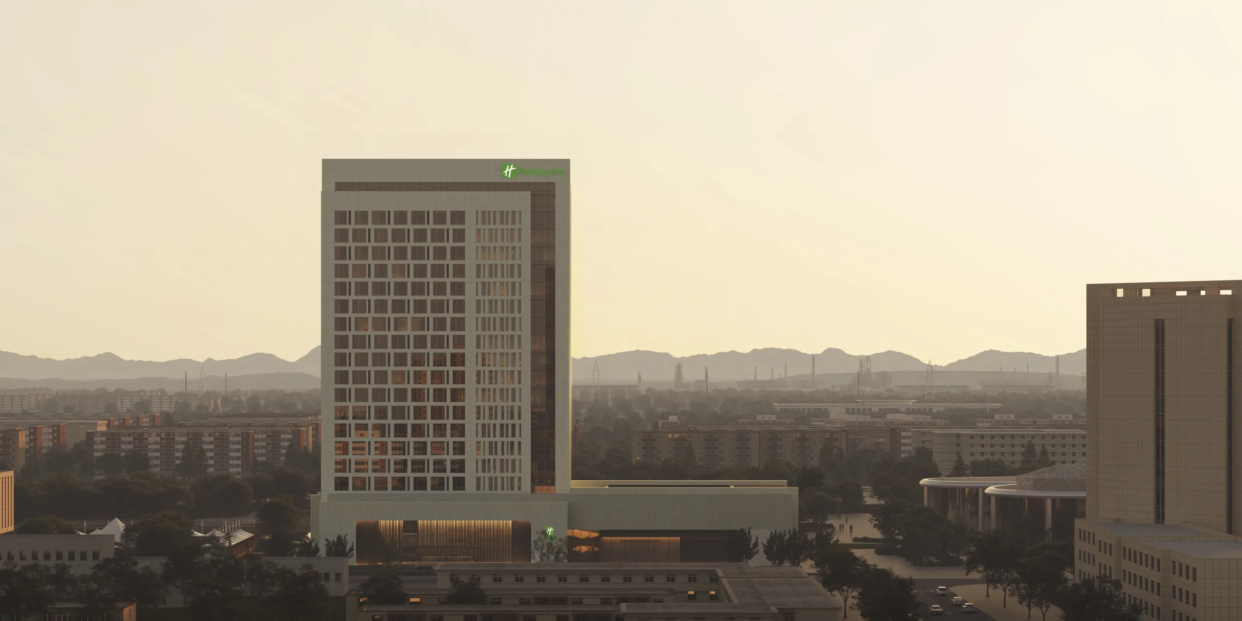 Aedas’ CGDG Xinjiang Beautiful China Resort Kuitun Holiday Inn Hotel is shown as a contemporary mid‑rise hotel tower rising from a horizontally layered podium facing an urban waterfront. The image highlights a restrained, rectilinear façade with a regular window grid, warm recessed podium lighting, and landscaped foreground spaces that establish the building as an open, civic‑oriented hospitality landmark, recalling the welcoming posture of historic Silk Road inns while anchoring a modern city living room.