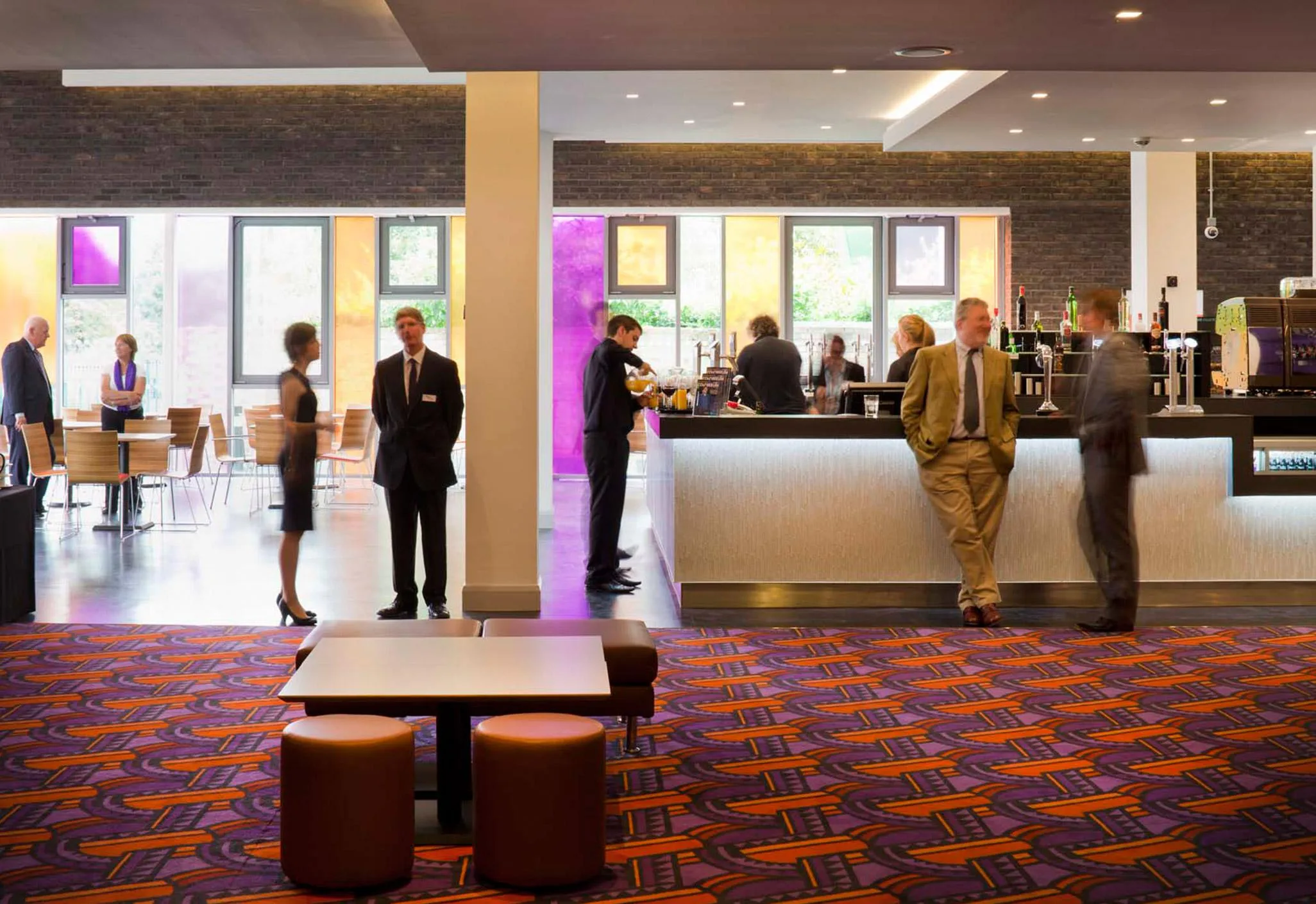 Aedas’s Watford Colosseum is shown with a reconfigured foyer architecture featuring open‑plan public space, expressed structural columns, full‑height glazing, brick wall finishes, and integrated lighting. The image highlights adaptive reuse architecture, civic cultural infrastructure, and performance‑support buildings upgraded for contemporary use in a UK urban setting.
