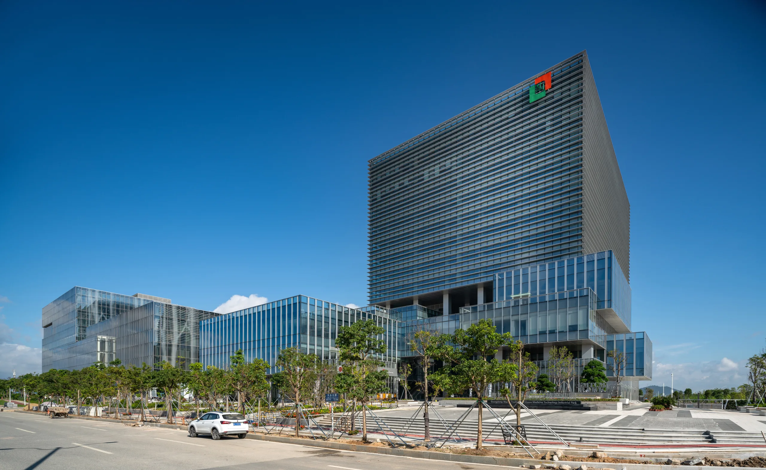 Aedas’s Headquarters for the Traditional Chinese Medicine Science and Technology Industrial Park in Zhuhai features interconnected towers with high-performance glazing, horizontal solar shading, and landscaped permeable paving. The subtropical climate context informs passive cooling strategies, net-zero energy design, and biophilic integration, reinforcing adaptive reuse potential and Passive House standards.