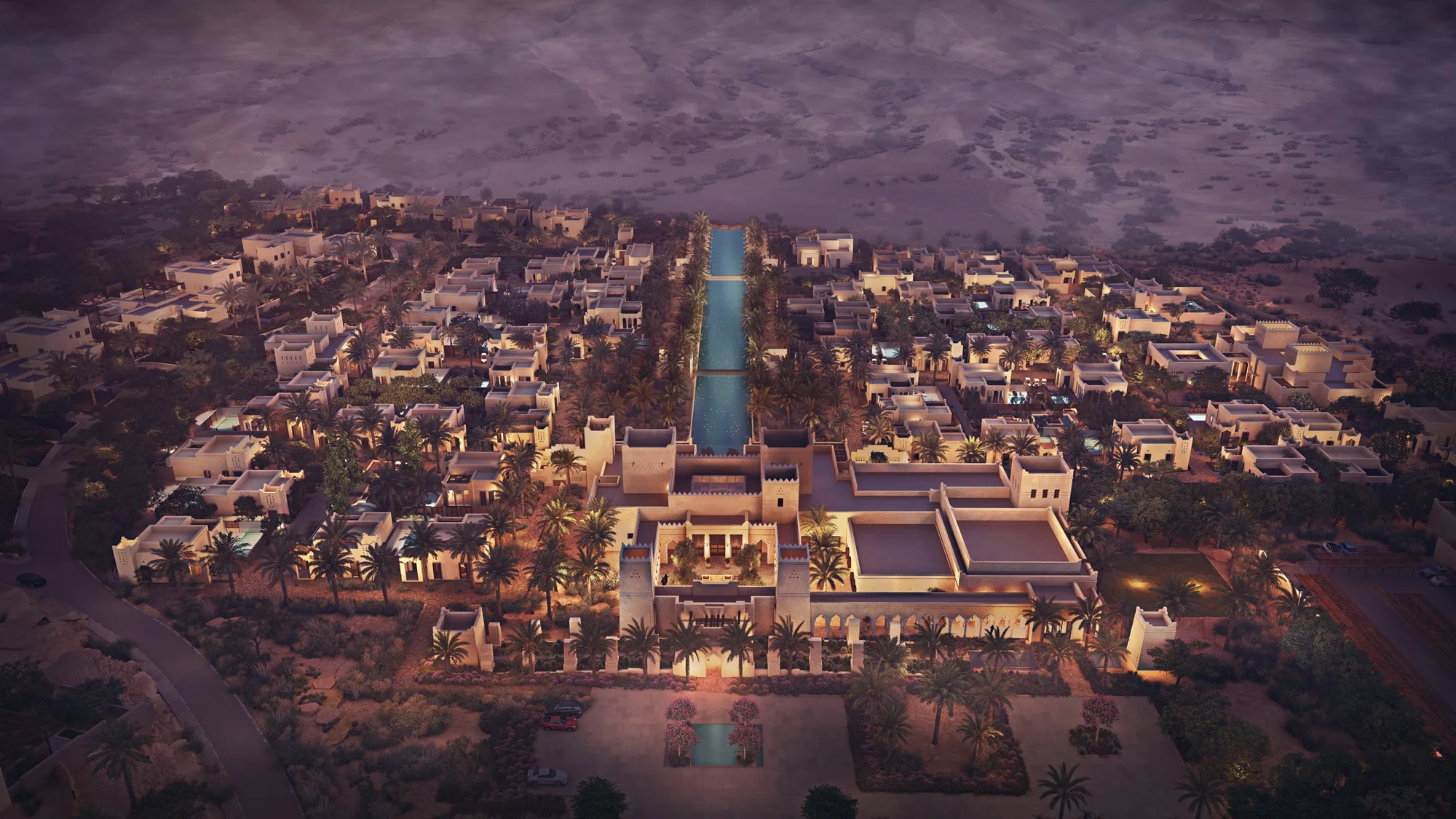 Aedas’ The Oberoi Wadi Safar—low-rise luxury resort with courtyard villas, palm groves and central water axis in desert terrain. Aerial dusk view of Aedas’ The Oberoi Wadi Safar in Saudi Arabia: low-rise resort villas organised along a linear water axis, framed by palm groves and courtyards. Earth-toned masonry volumes sit within desert topography, forming shaded pedestrian paths. Visible planning supports courtyard-based passive cooling, climate-responsive resort design and landscape-integrated luxury hospitality.
